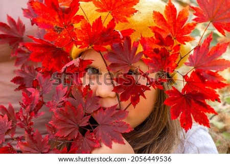 little girl behind bright maple autumn leafs