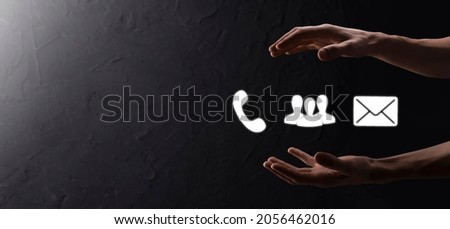 Hand hold icon symbol telephone, email, contact. Website page contact us or e-mail marketing concept on dark beton background.