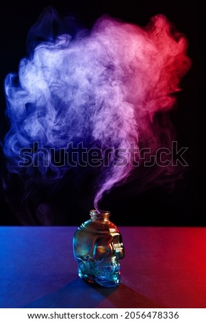 Stained glass skull, colored smoke, colored blue-red light. Halloween concept