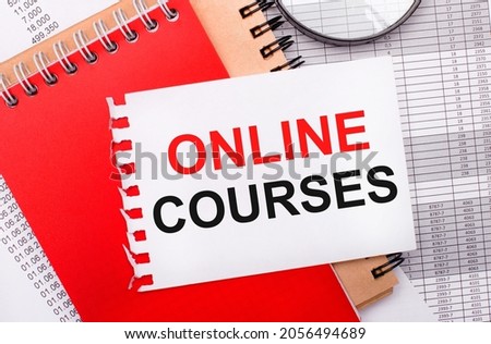 On a light background - reports, a magnifying glass, brown and red notepads, and a white notepad with the text ONLINE COURSES. Business concept