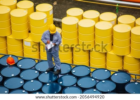 Male worker inspection record drum oil stock barrels yellow vertical or chemical for transportation truck male in the industry. Royalty-Free Stock Photo #2056494920