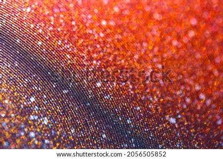 Shimmering red sandy background with wavy texture and blur. Macro image of a metallic shiny surface