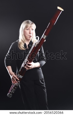 Bassoon woodwind instruments player. Classical musician woman playing orchestral bass. Wind instrument Royalty-Free Stock Photo #2056520366
