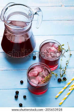 Cold refreshing berry drink with ice and thyme on the blue wooden table