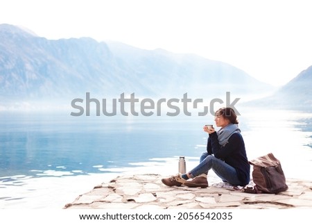 Woman drinking coffee and relaxing at sea beach. Winter picnic and rest Royalty-Free Stock Photo #2056542035