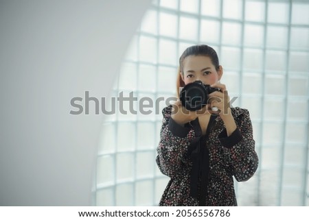 Woman in black with small flower pattern dress using digital camera taking her photo at the mirror with copy space.