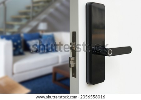 Digital Door handle or Electronics knob for access to room security, Door wooden half opening through interior living room background, selective focus                    
