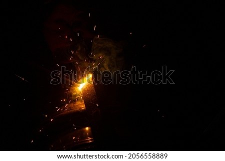 Close-up of a welder working in a workshop. Shallow depth of field. Welding of metal structures. Semi-automatic manual welding. MIG welding. 