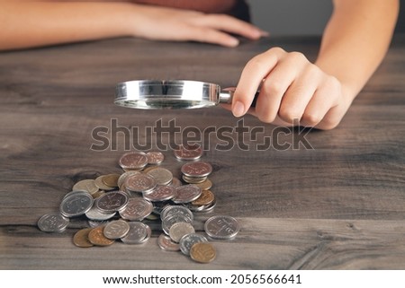 woman looking at coins with a magnifying glass