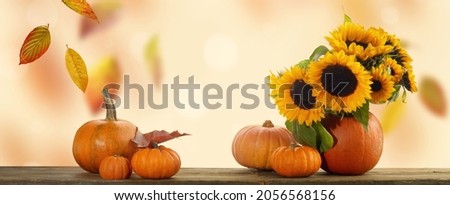 Thanksgiving pumpkins, autumn leaves and berries on wooden table. Autumn background with falling leaves.
