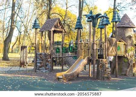 Empty outdoor children's wooden playground with swings in the forest in the autumn outdoors with nobody