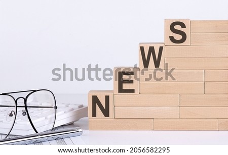 wooden cubes with letters NEWS on white table with keyboard and glasses