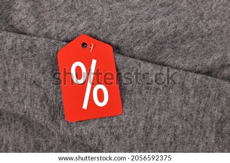 Red percentage sign sale label attached to gray clothing