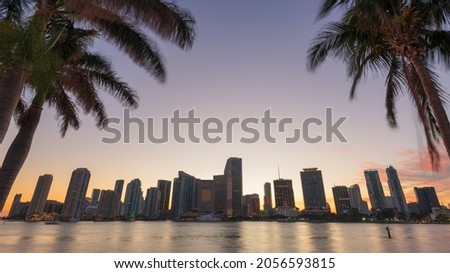 Miami, Florida, USA skyline on Biscayne Bay with palms at dusk.