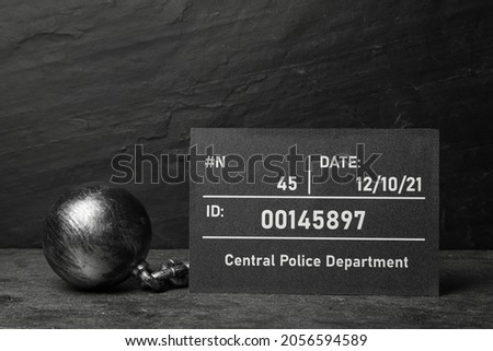 Metal ball with chain and mugshot letter board on grey table