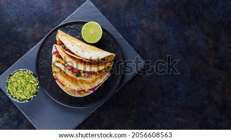 Vegetarian tacos with sweet corn, purple cabbage and tomatoes on a black plate. Tacos with vegetables and guacamole sauce on dark background. Copy space. Top view