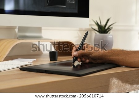 Professional retoucher working on graphic tablet at desk, closeup