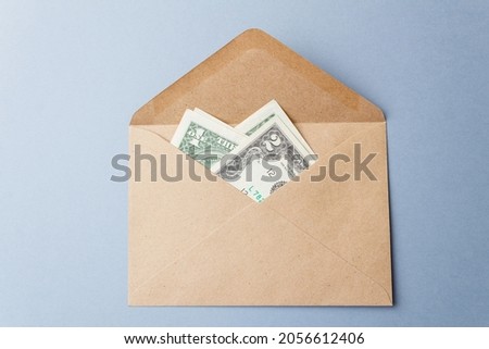 Banknotes are dollars in a paper envelope. An open envelope with banknotes on the table on a gray background. International monetary currency. Close-up. Top view.