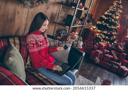 Photo of attractive pretty young lady wear red pullover smiling buying christmas presents modern device indoors house home room