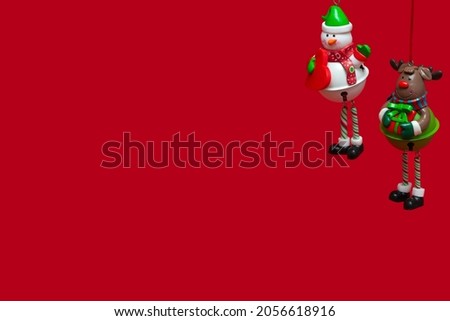 Isolated hanging Christmas toys on a red background: snowman and snow deer. concept for New Year greeting card, invitation and packaging. Banner.