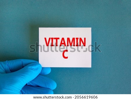Vitamin C symbol. White note with words Vitamin C, beautiful blue background, doctor hand in blue glove. Medical, vitamin C concept.