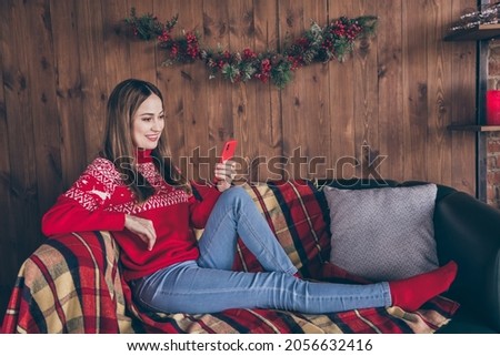 Photo of charming cute young woman dressed red sweater reading modern device new year congratulations smiling indoors room home house