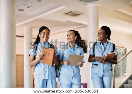 Multi-ethnic group of happy nursing students walking through medical university corridor. 