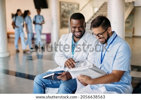 Happy African American medical student and his friend studying in corridor at medical university.