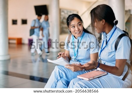 Multiracial medical students communicating while learning at university hallway. Focus is on Asian student.