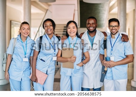 Multi0ethnic group of happy medical and nursing students standing in a hallway at medical university and looking at camera. 
