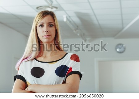 Attentive businesswoman staring intently at the camera with folded arms and a determined expression in close up