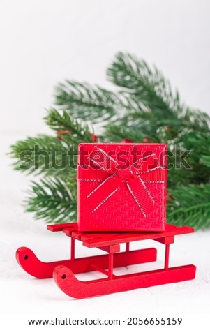 Red gift box on a Santa sleigh, Christmas tree branches on background