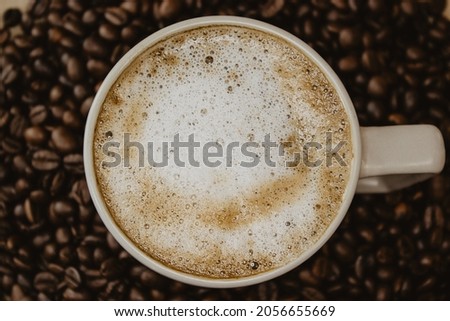 Still Life of cup of coffee at the bottom of the coffee beans on brown background. Still Life Coffee Photography. 