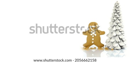 Christmas banner with standing gingerbread man cookie and tree against a white background.