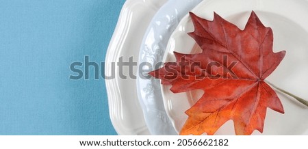 Holiday Thanksgiving banner with dining table elegant place setting in pale aqua blue and white theme with autumn leaf, with copy space.