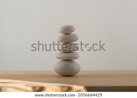 Stone cairn on white background, five stones tower, simple poise stones, simplicity harmony and balance, rock zen sculpture tower