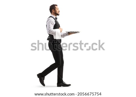 Full length profile shot of a waiter carrying a silver tray and walking isolated on white background Royalty-Free Stock Photo #2056675754