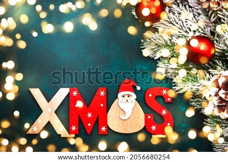Blue Christmas or New Year background with red and blue Christmas balls, garland lights, golden bokeh and inscription Xmas, top view