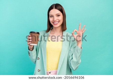 Portrait of charming positive girl hold paper coffee cup fingers show okey isolated on teal color background