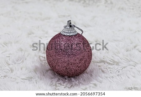 Christmas glittering pink ball on white fur background.