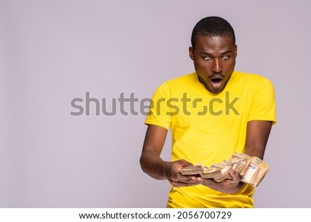 young black man holding a lot of cash looks surprised and amazed Royalty-Free Stock Photo #2056700729