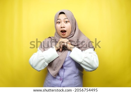 Beautiful young asian muslim woman shocked, surprised, wow expression, isolated on yellow background
