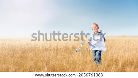 Little boy running in the open air.
Cheerful and happy child play and launch a kite in the field against the blue sky. Kid dream of flying and aviation in a retro style.