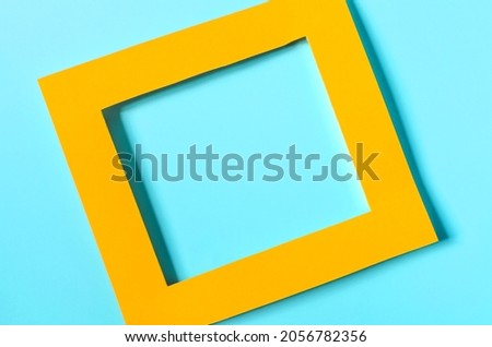 Yellow paper frame on a colored background. Flat bright yellow frame on a light green background close-up
