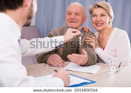 Mature woman and elderly man signing contract of rent apartments and hand over keys