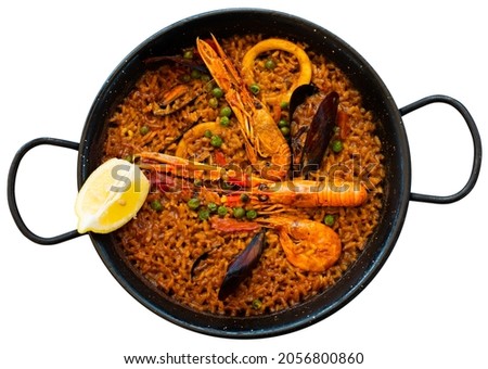 Appetizing national dish of Spanish cuisine paella with seafood, made from rice with squid, .shrimp, mussels and garnished with lemon. Isolated over white background