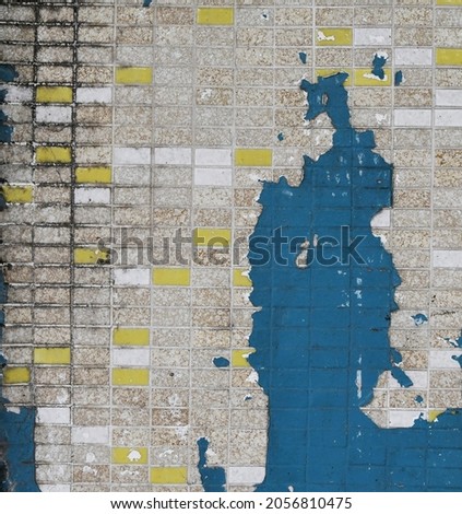 Old cracked damaged weathered blue paint exposed urban exterior tile wall