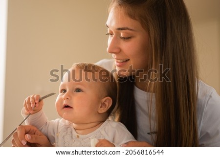 Beautiful mother is helping her baby to get rid off the fork she is holding