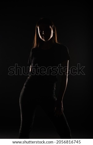 Silhouette of young and beautiful girl posing in studio on grey background, close up