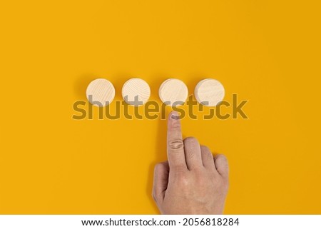 The circular wooden block is placed on a yellow background with a hand pointing at the wooden block. Wood block concept, banner with copy space for text, poster, mockup template.